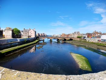 Bridge over river against buildings in city