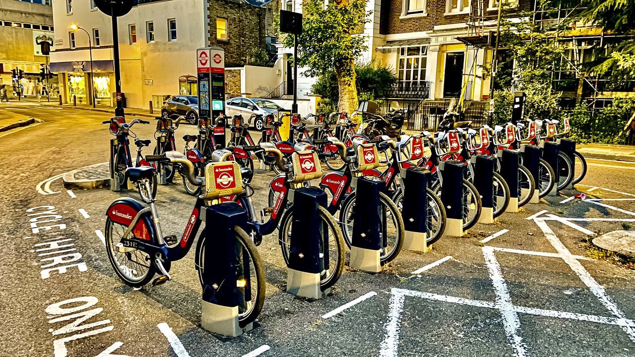 city, architecture, street, crowd, bicycle, building exterior, transportation, built structure, musician, in a row, road, day, vehicle, marching, person, mode of transportation, road marking, outdoors, large group of people, land vehicle, group of people, sign, government, symbol, marking, security, uniform