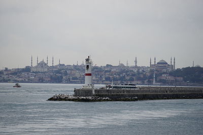 View of lighthouse by buildings in city