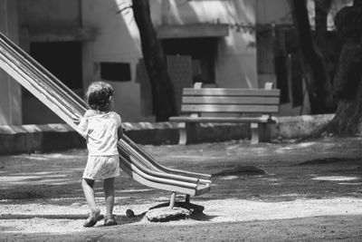 Full length of girl standing by slide at playground