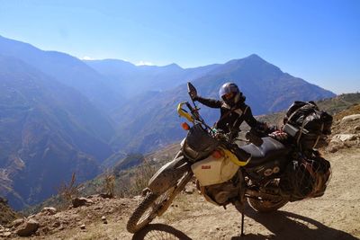 Man riding motorcycle on landscape against mountain range