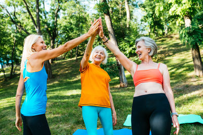 Rear view of woman with arms raised standing in park