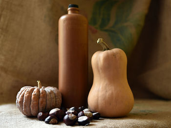 Close-up of chestnuts and pumpkins by bottle on table