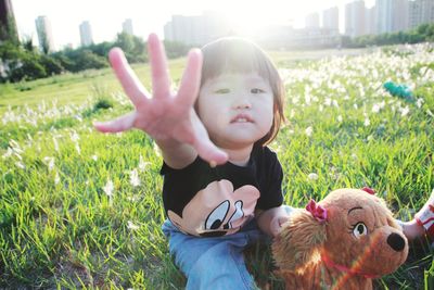 Portrait of cute girl with toy sitting on grassy land