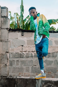 Portrait of young man standing against wall