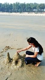 Side view of woman sitting on beach