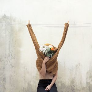 Midsection of woman holding umbrella standing against wall