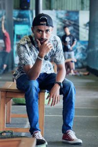 Portrait of young man sitting on stool