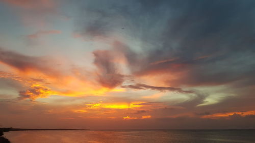 Scenic view of sea against dramatic sky during sunset