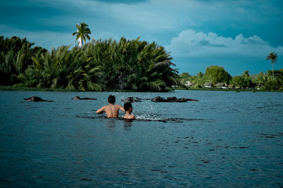 Friends enjoying in water against sky