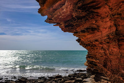 Rock formation by sea against sky