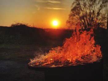 Bonfire on field against sky at sunset