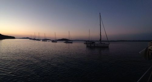 Sailboats in sea at sunset