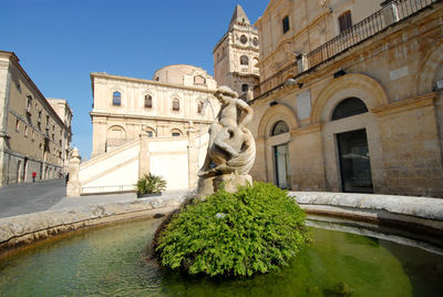 Statue amidst buildings against sky in city