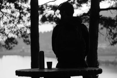 Rear view of silhouette man looking at lake