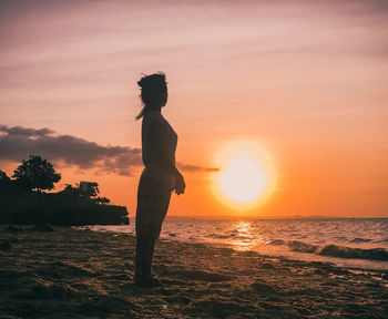 Side view of man standing on beach during sunset