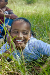 Portrait of a little boy lying on a grass field 