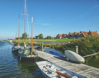 Boats moored on river against clear blue sky