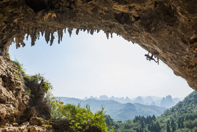 Man climbing the arch at odin's den next to moon hill in yangshuo