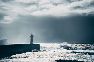 Lighthouse by sea against sky