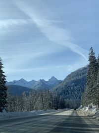 Road by snowcapped mountains against sky