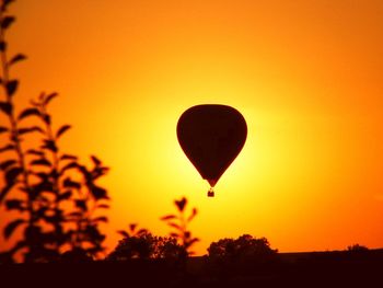 Silhouette hot air balloon against orange sky