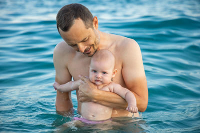 Father with baby standing in sea