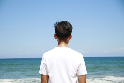 Rear view of man looking at sea against sky