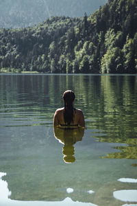 Rear view of woman in lake at forest