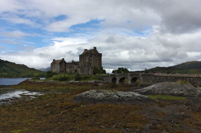 Eilean donan castle at low tide against cloudy sky