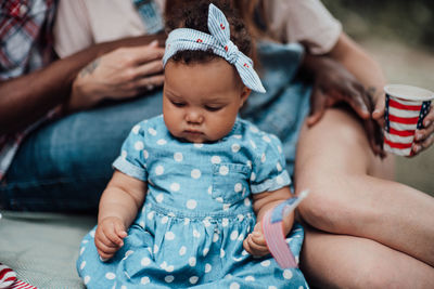 Midsection of mother and baby girl sitting outdoors