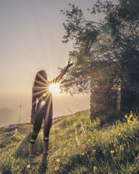 Woman standing on field against bright sun