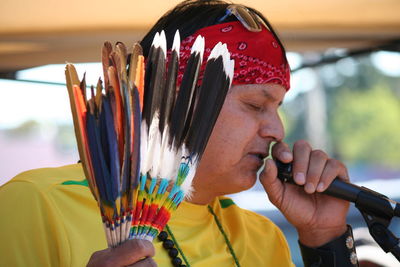 Close-up of mature man talking on microphone while holding feathers