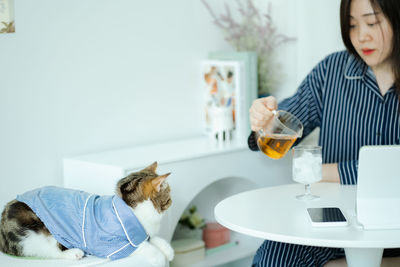 Woman in pajamas cloth drink tea and play with her cat