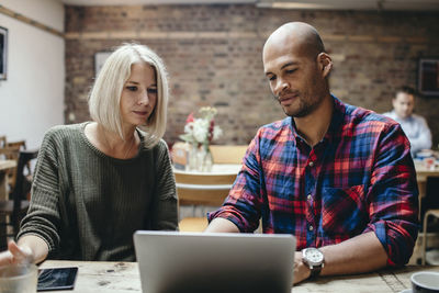 Couple using laptop at table in coffee shop