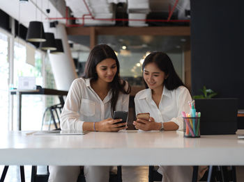 Businesswomen using smart phone while sitting at office