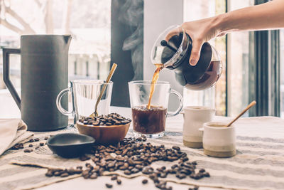 Cropped hand of woman holding coffee on table