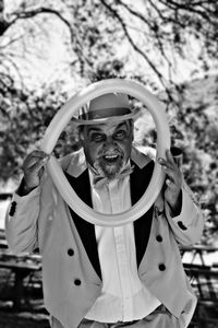 Portrait of mature man looking through folded balloon at park