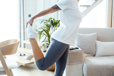 Low section of woman sitting on sofa at home