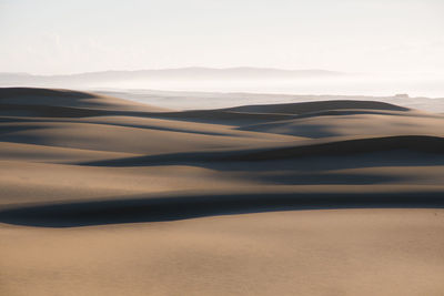 Scenic view of sand dunes against sky