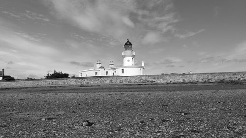 Lighthouse on beach against sky