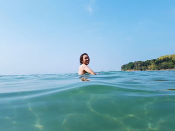Smiling young woman in sea against sky