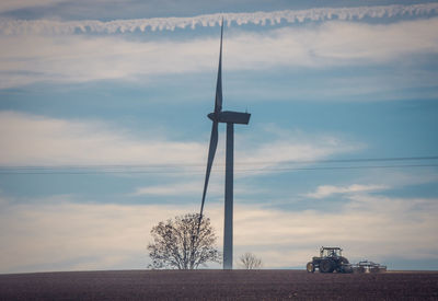 Wind turbines on field against sky