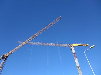 Low angle view of crane against clear blue sky