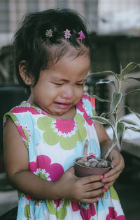 Girl crying while holding potted plant