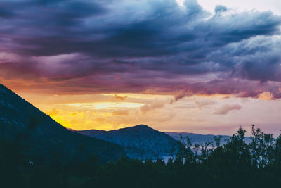 Scenic view of silhouette mountains against dramatic sky