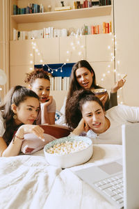 Multiracial friends watching movie together on laptop at home