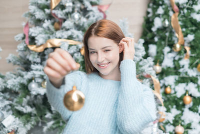 Portrait of young woman holding christmas decoration