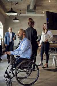 Businessman with disability near colleagues in creative office