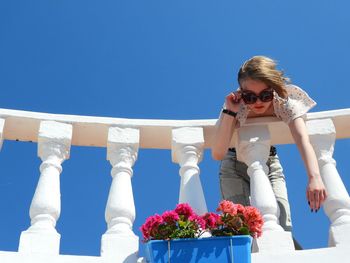 Side view of woman standing against blue sky